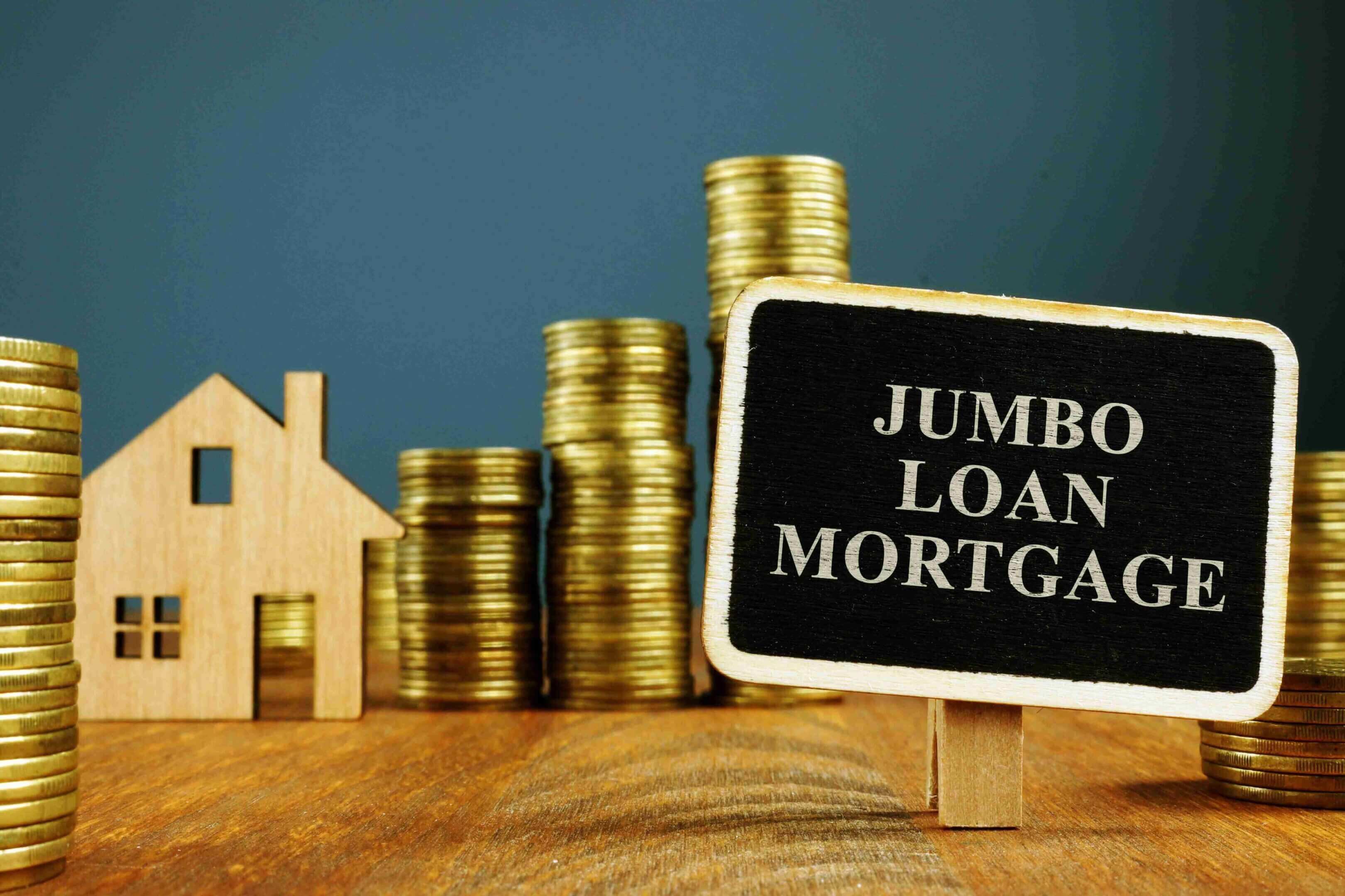 Stacks of coins and a small house model next to a sign reading 'Jumbo Loans Mortgage'.