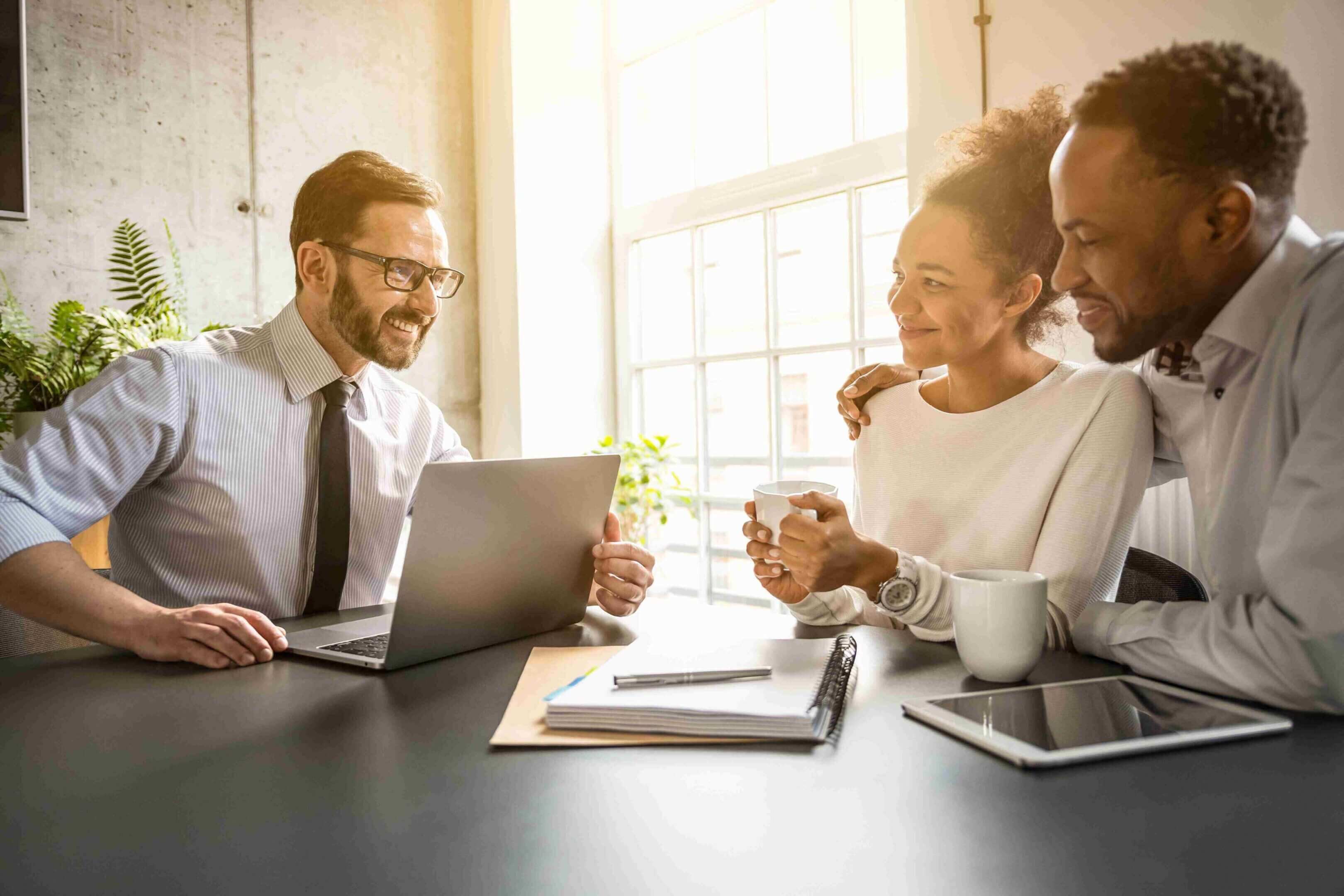 A professional man consulting with a happy couple in a bright office.