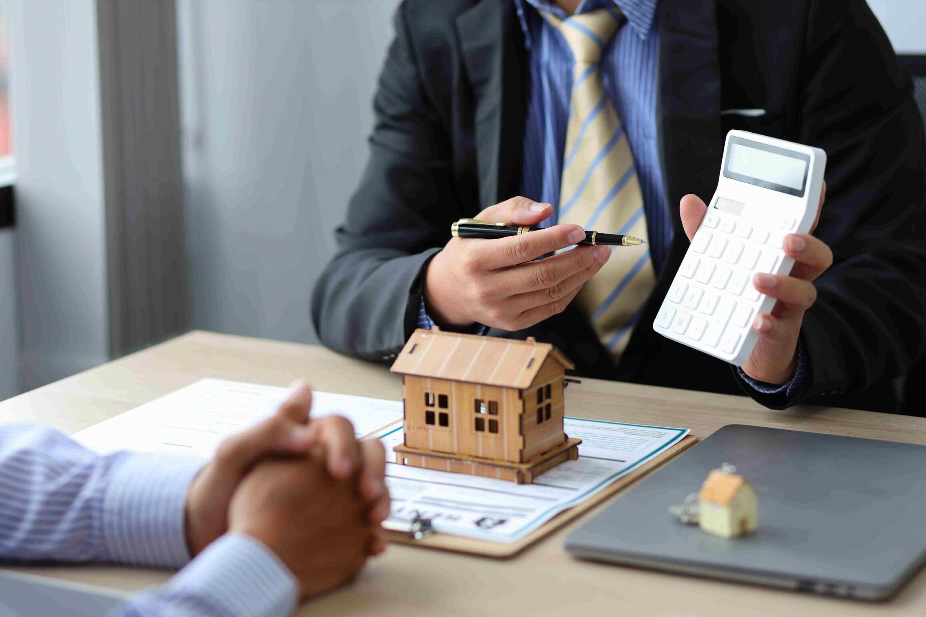 A real estate agent showing a house model to clients.
