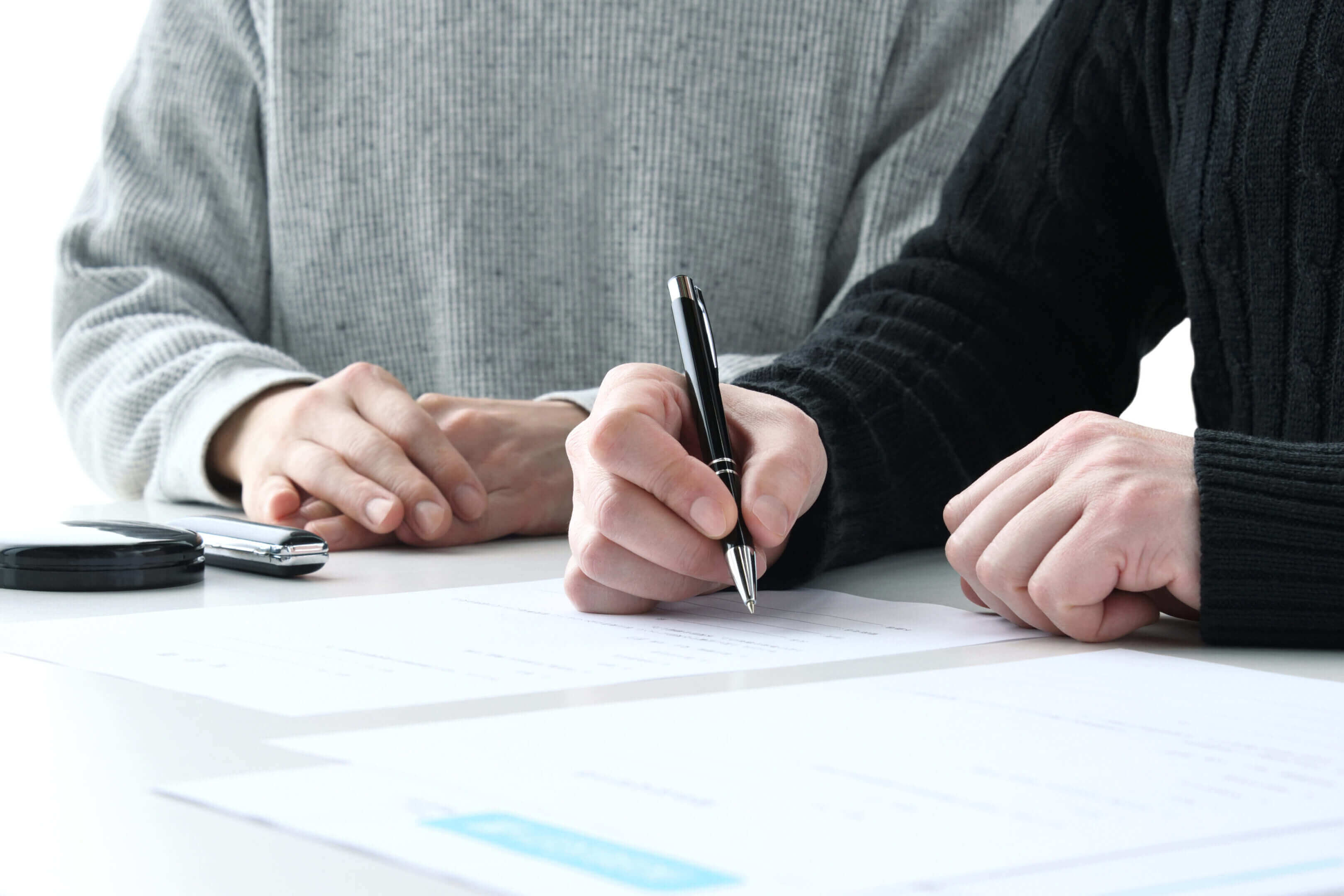 Two people signing documents at a table.