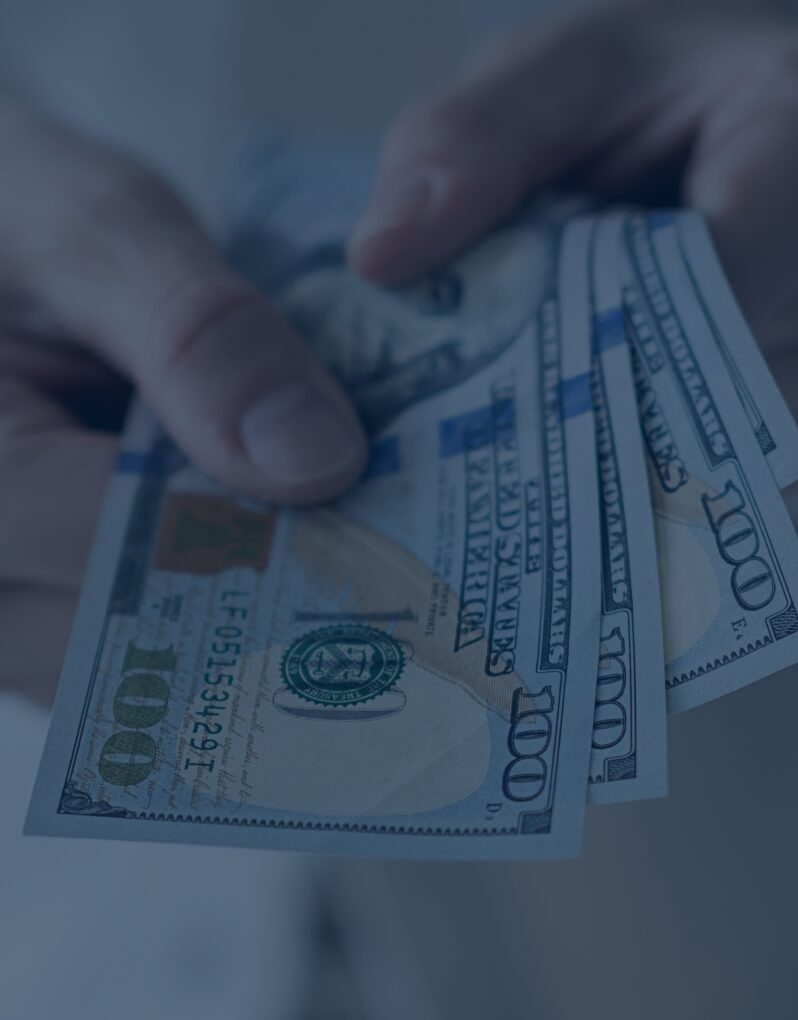 Hands counting multiple $100 bills.