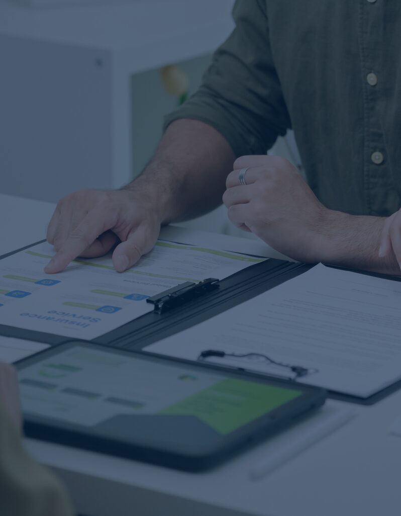 Person pointing at charts and documents during a meeting.