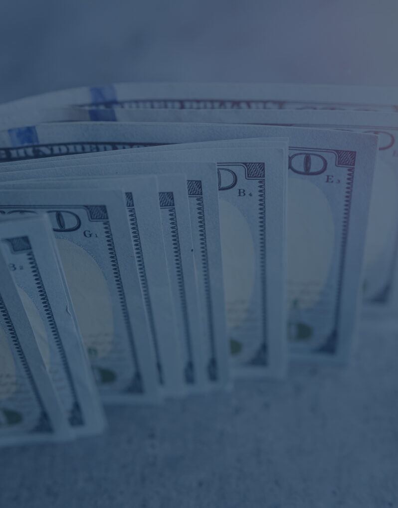 Several stacks of US $100 bills arranged in a fanned-out pattern.