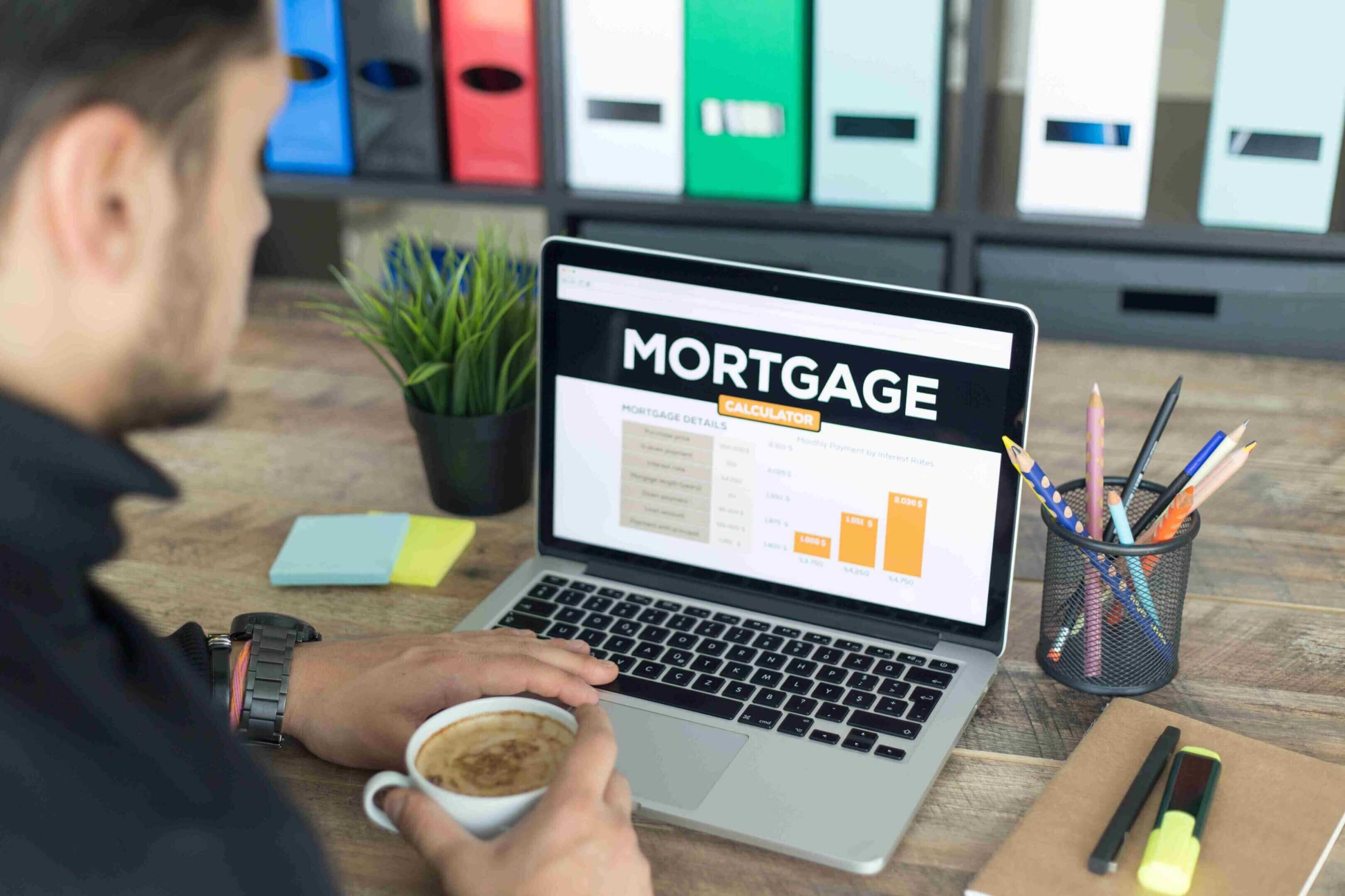 Person reviewing mortgage details on a laptop with coffee.