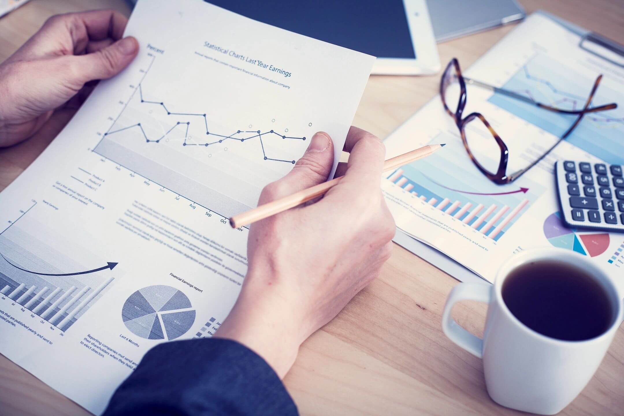 Person analyzing financial charts and graphs at a desk.