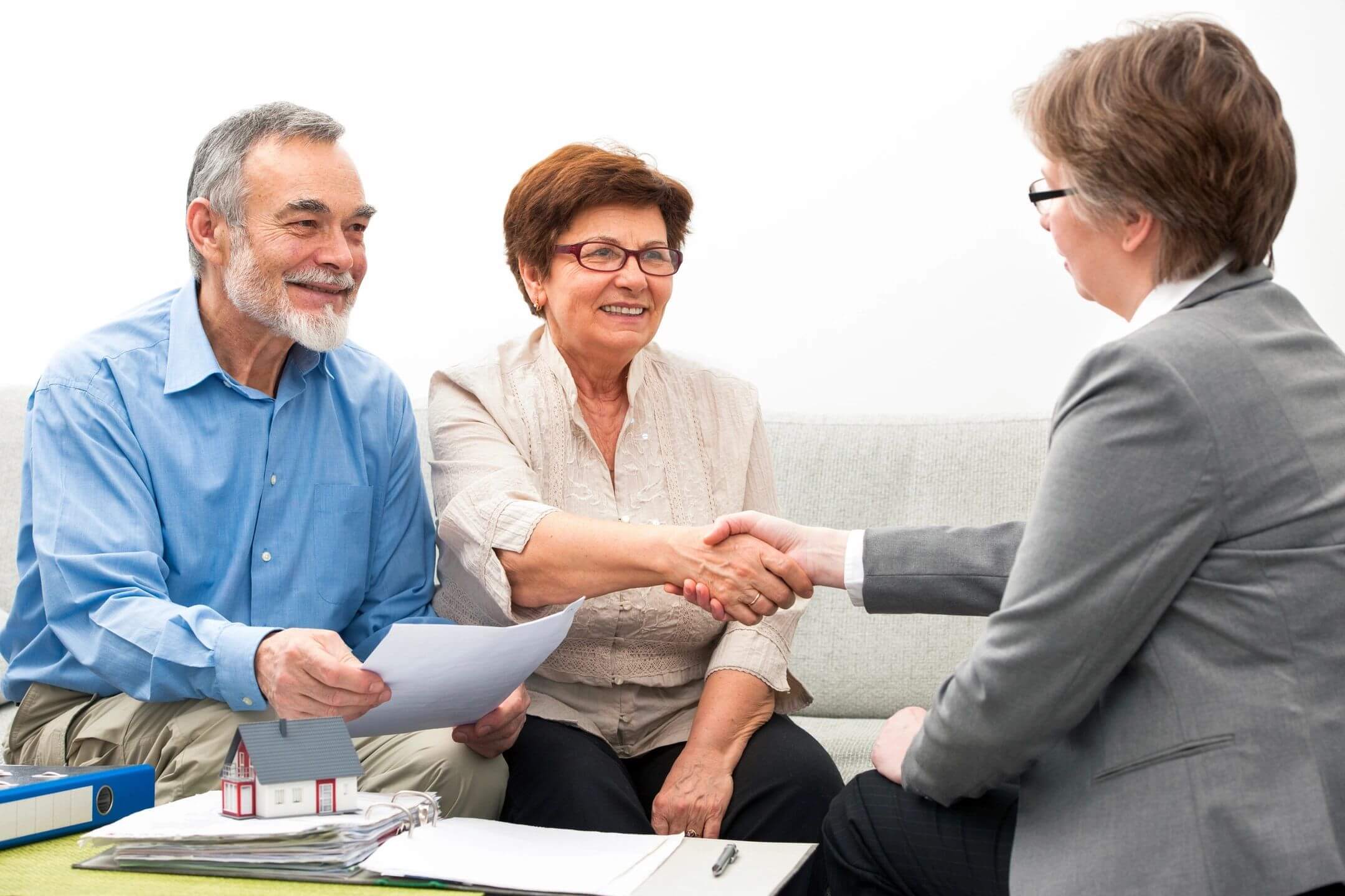 Senior couple shaking hands with a professional in a consultation.