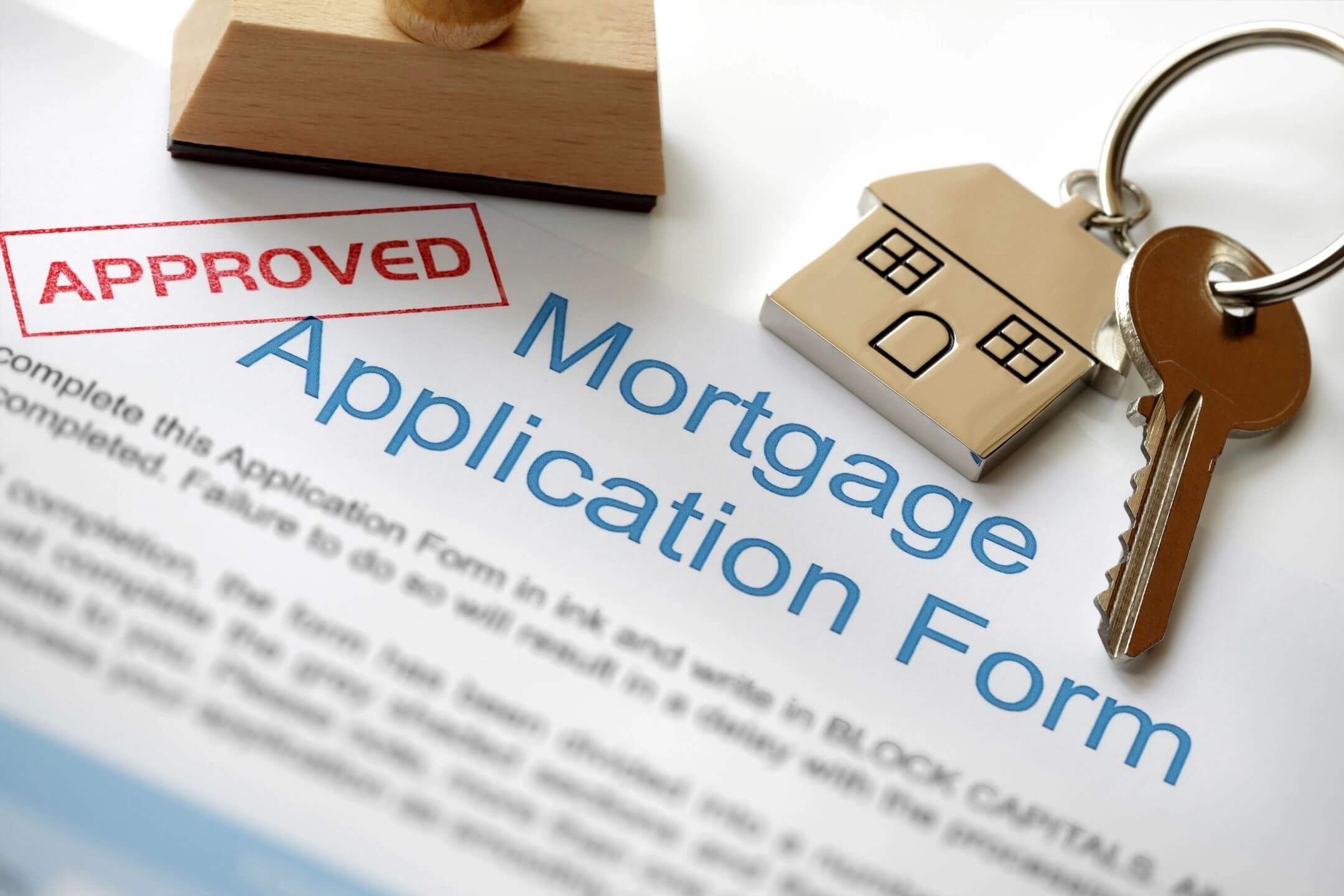 Mortgage application form with a small wooden house and stamp.