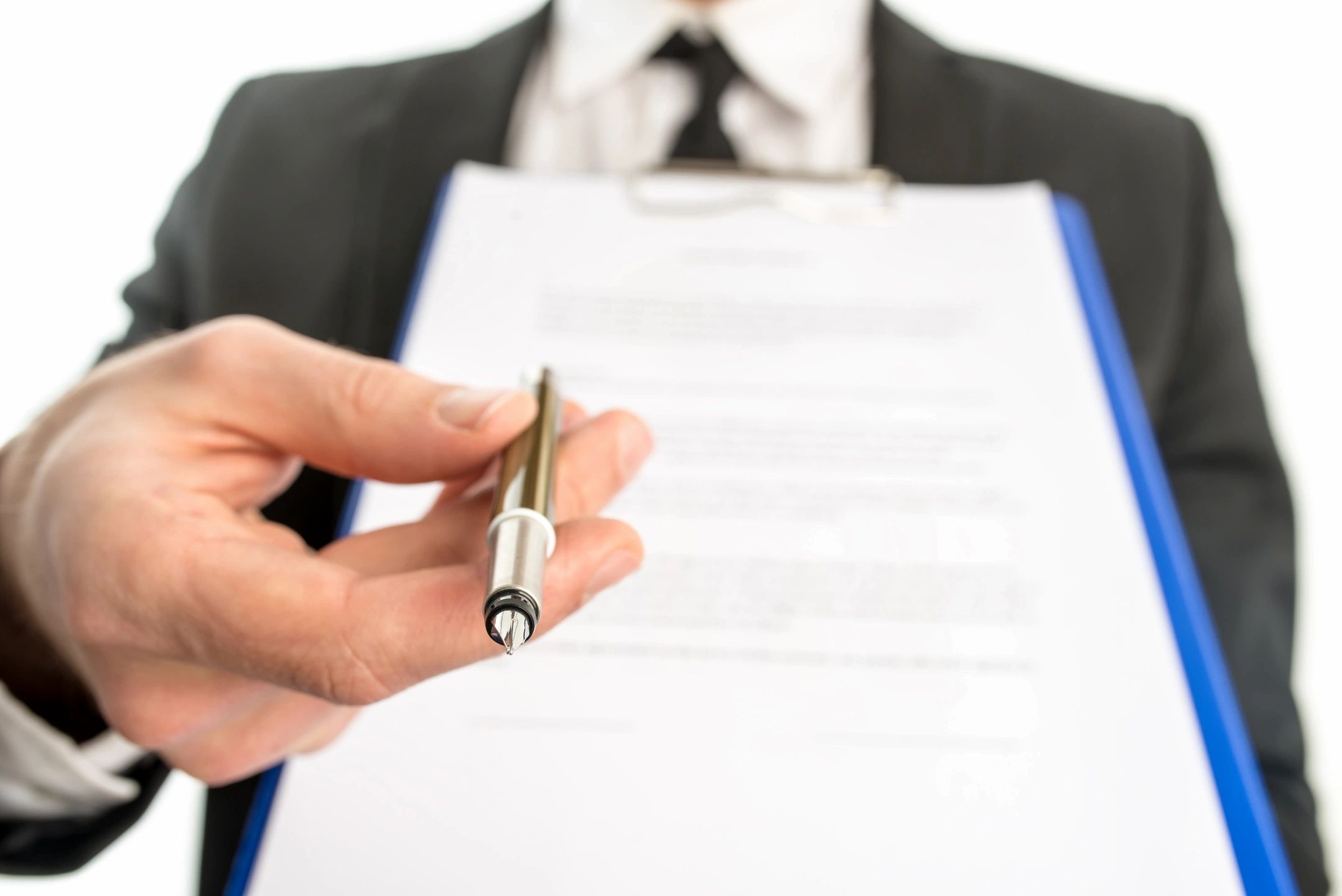 Person offering a pen to sign a document held on a clipboard.