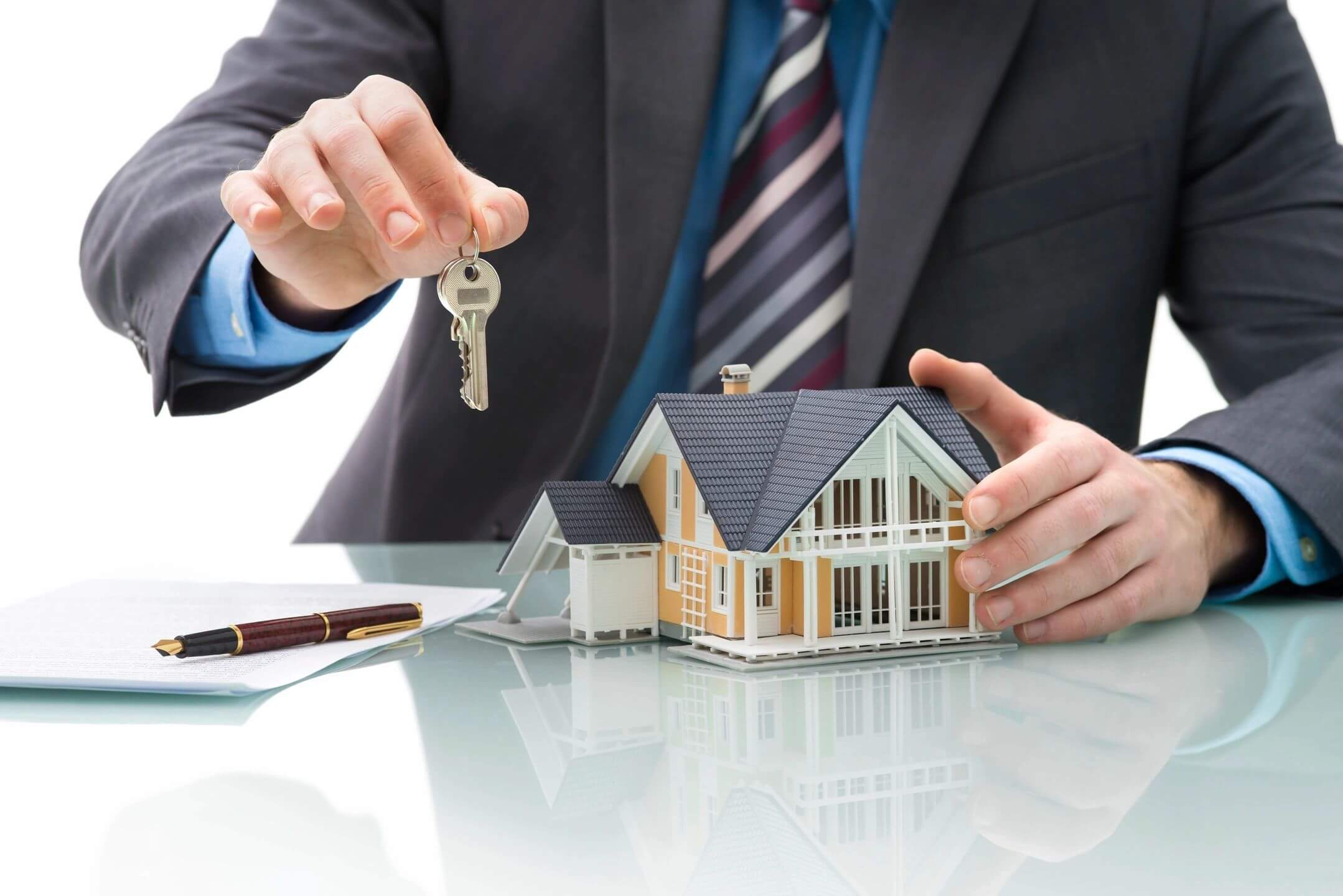 Real estate agent presenting house keys and a model home.