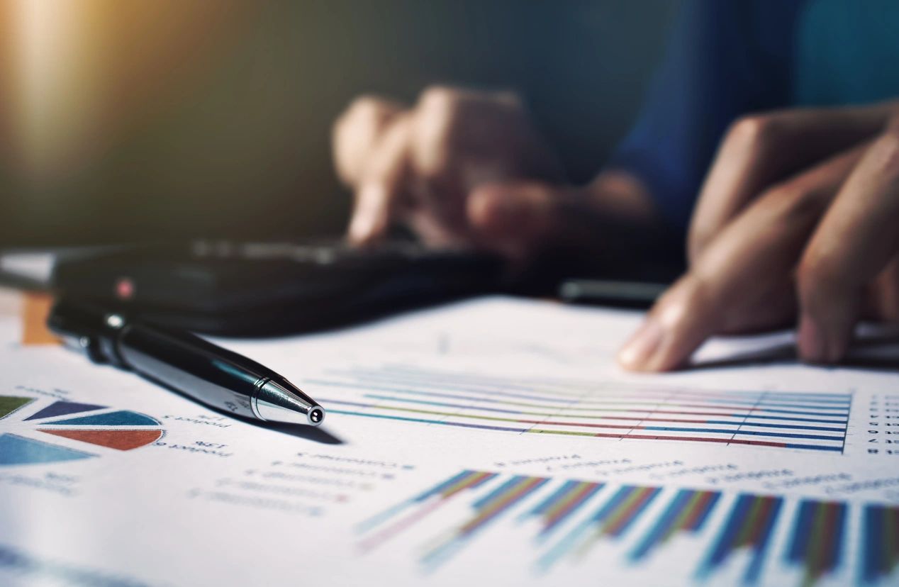 Person analyzing financial charts and data with a pen.