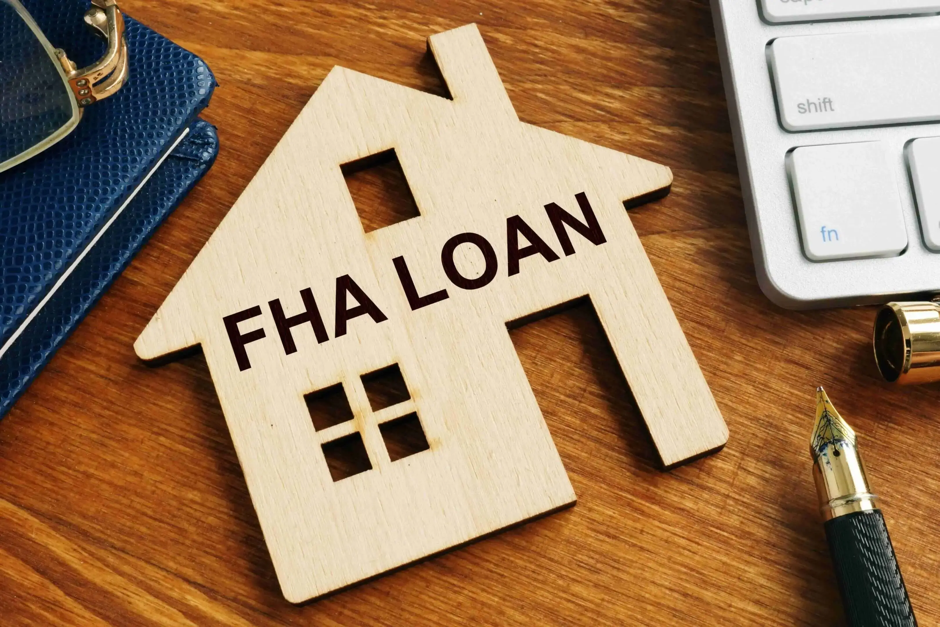 Wooden house model with 'FHA LOAN' text symbolizing home financing.